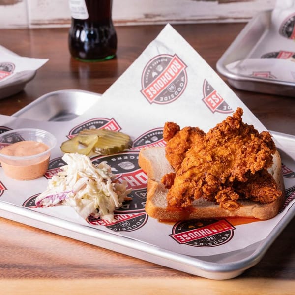 Woodside Roadhouse fried chicken tenders on white bread with coleslaw, pickles, and sauce.